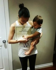 Mia holding her RYT200 Certificate with her son